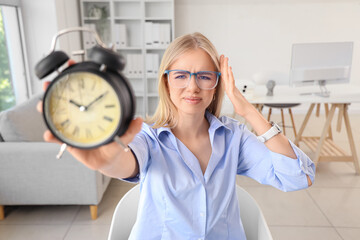 Canvas Print - Stressed young businesswoman with alarm clock working under deadline in office, closeup