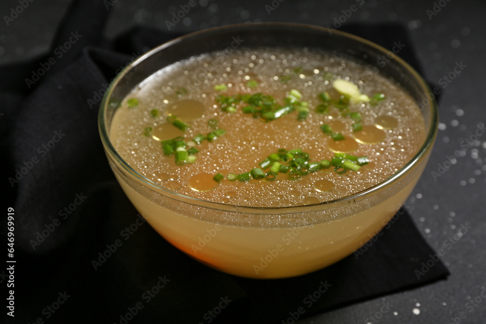 Bowl of tasty vegetable broth on black background