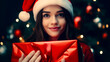 © Констянтин Батыльчук - Woman in santa hat is holding red present in front of christmas tree.