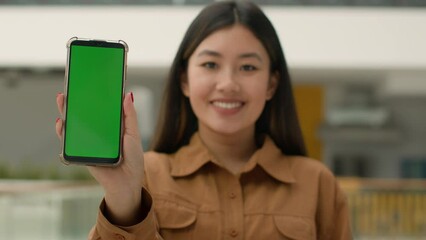Mobile phone device focus blurred Asian business woman chinese girl hold smartphone green mock-up happy businesswoman advertise cellphone chroma key empty display web service cell gadget advertisement