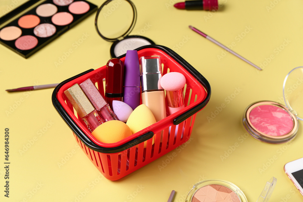 Shopping basket with makeup cosmetics on beige background, closeup