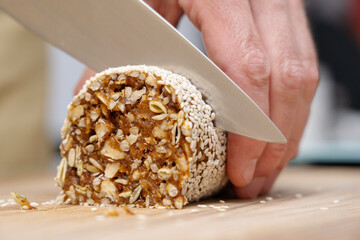 Wall Mural - Natural dessert made from dates and sunflower seeds is cut with a knife on a board. 