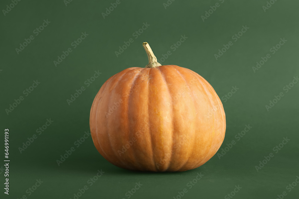 Raw pumpkin for Halloween celebration on green background