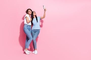 Sticker - Full body length cadre of two friendly charming girls sisters spend free time shopping mall selfie camera isolated on pink color background