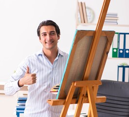 Wall Mural - Young handsome employee enjoying painting at the office