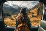 Fototapeta Tulipany - Cinematic and symmetrical beautiful back view shot of female traveler, travel blogger and inspired adventurer hang out of train window, look at amazing landscape of autumn mountains,