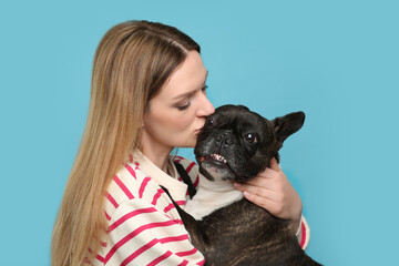 Poster - Woman hugging cute French Bulldog on light blue background