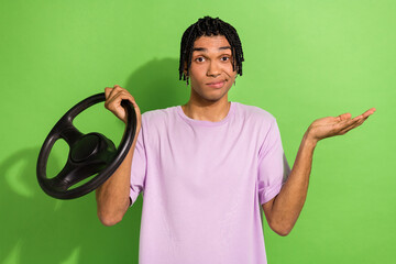 Sticker - Photo of clueless young man arm hold wheel shrug shoulders not know isolated on green color background