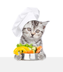 Aufkleber - Tabby cat wearing chef's hat holding bowl of vegetables above empty board. isolated on white background