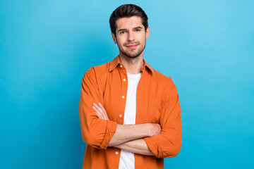 Poster - Photo of cheerful attractive man dressed orange shirt arms folded smiling isolated blue color background