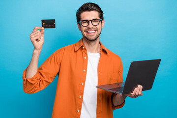 Aufkleber - Photo of cheerful handsome guy toothy smile hold showing debit plastic card use netbook isolated on blue color background