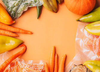 Wall Mural - Ripe vegetables and frozen chopped vegetables in a vacuum bag on an orange background.