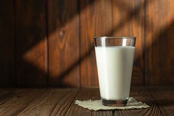 Canvas Print - milk in glass on wooden table with sun rays