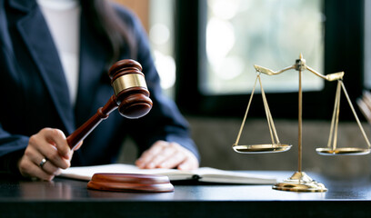 justice and law concept.Female judge holding wooden gavel in a courtroom on wooden table