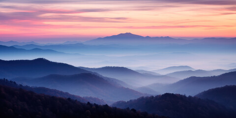 The mountains are shrouded in mist, and the last traces of daylight lend a tranquil, mystical quality to the scene. A twilight shot of autumn mountains under a fading pink and purple sky.