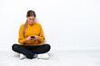 © luismolinero - Young caucasian woman sitting on the floor isolated on white background sending a message with the mobile