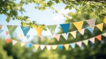 Colorful Pennant String Decoration In Green Tree Foliage On Blue Sky With Copy Space.