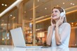 © StockPhotoRepublic - Young caucasian woman wearing headphone using laptop at a local cafe