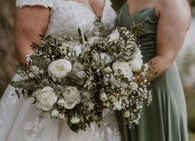 Close up of bouquets in hands of a bride and bridesmaid in green and white