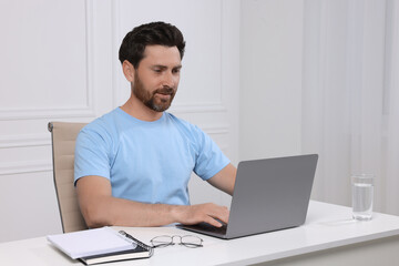 Poster - Man using laptop at white table indoors