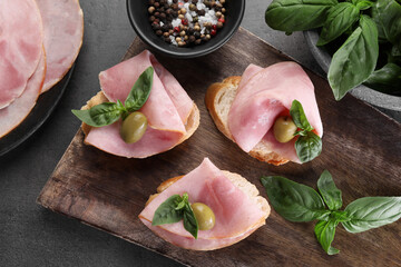 Wall Mural - Delicious sandwiches with ham, basil, olives and spices on grey table, flat lay