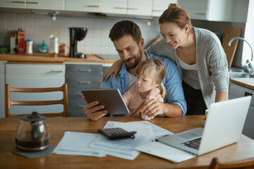 Wall Mural - Young Caucasian family using a tablet in the kitchen in the morning