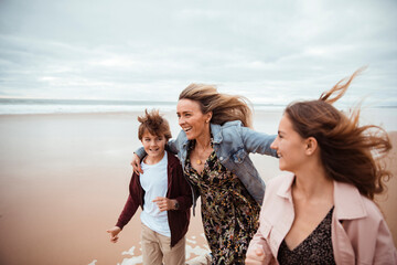 Wall Mural - Single mother taking her kids for a walk on a sandy beach in Lisbon