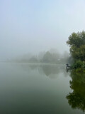 Fototapeta Na ścianę - Mystical morning at the fog-kissed lake, where nature's beauty emerges through the ethereal mist.