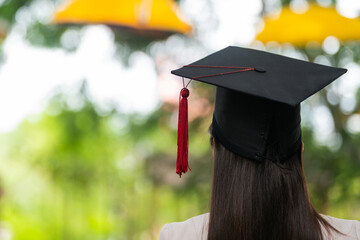 Wall Mural - Young happy Asian woman university graduate in graduation gown and cap in the college campus. Education stock photo