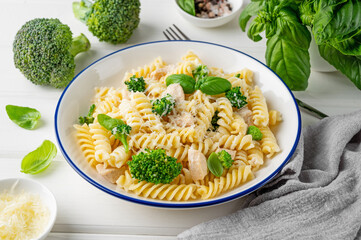 Wall Mural - Delicious broccoli and chicken fusilli pasta with parmesan cheese and fresh basil in a bowl on a white wooden background. Healthy comfort food.