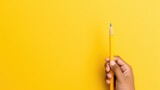 Fototapeta  - Hand holding pencil isolated yellow background. AI generated