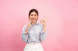 © Katcha - Young asian woman wearing long sleeve shirt and smiling while touching forefinger on the face and showing ok