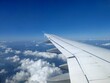 Flügel eines Flugzeugs mit blauem Himmel und Wolken