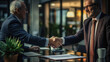 © Microgen - A handshake between a financial advisor and a client in an upscale financial office.