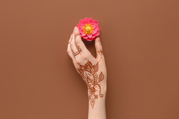 Female hand with lotus flower for celebration of Divaly on brown background