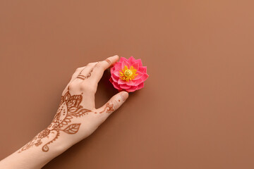 Wall Mural - Female hand with lotus flower for celebration of Divaly on brown background