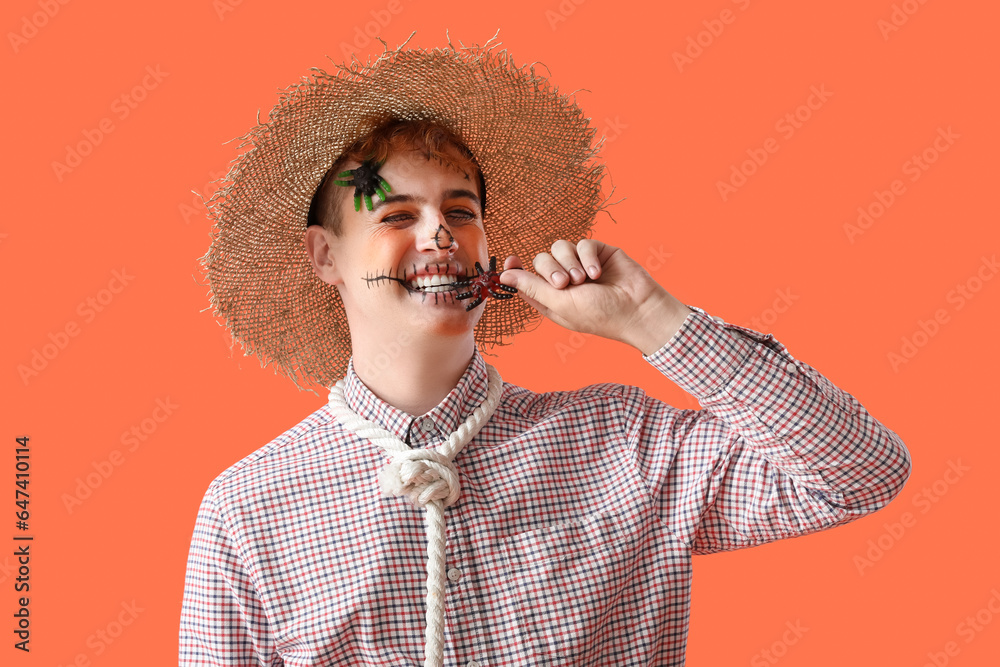 Young man dressed for Halloween eating candy on red background