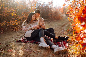 Wall Mural - Young man and woman are walking, spending time together in the autumn forest. Beautiful couple enjoying nature outdoors in autumn. Concept for style, fashion, love or relaxation.