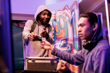 Poster - African american developer giving computer worm on ssd to asian hacker for password cracking. Criminal in hood bringing hard drive with dangerous illegal malicious software