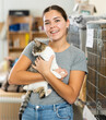 © JackF - Happy caring young girl holding curious white and gray cat in arms while visiting shelter for abandoned animals. Pet adoption concept