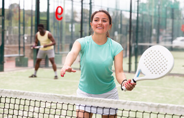 Wall Mural - Portrait of cheerful woman paddle tennis player during friendly doubles couple match with male friend at court