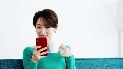 Leinwandbilder - リビングでスマホを見る女性