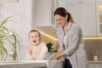 Wall Mural - Mother washing her little baby in sink at home