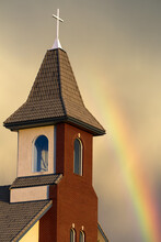 Church Steeple With Orange Glow From The Sunset And Rainbow In The Sky; Calgary, Alberta, Canada