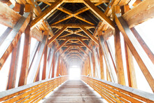 Wooden Bridge With Sunlight Glowing At The End; Golden, British Columbia, Canada