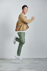 Wall Mural - Happy excited young Asian man jumping isolated on white studio background