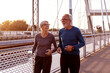 Senior adults jogging at the end of the day in sportsware on the bridge
