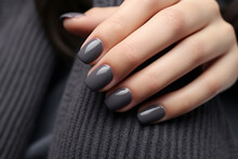 Closeup woman hand with dark gray and black nail polish on fingernails. Nail manicure with gel polish at luxury beauty salon. French manicure. Nail art and design. Female hand model.