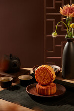 Two Moon Cakes Stacked On Top Of Each Other Decorated With A Tea Set And A Black Pot Of Flowers. Tasty Round Moon Cakes At Mid Autumn Festival
