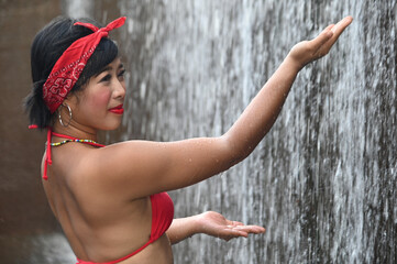 Wall Mural - A pretty Asian female in a swimsuit sits, standing , relaxes and shows off her expressions of fun. At a spillway in Thailand.